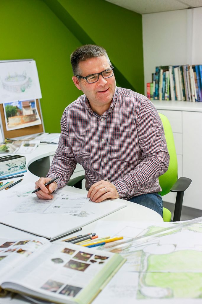 George smiling, working at desk on designs