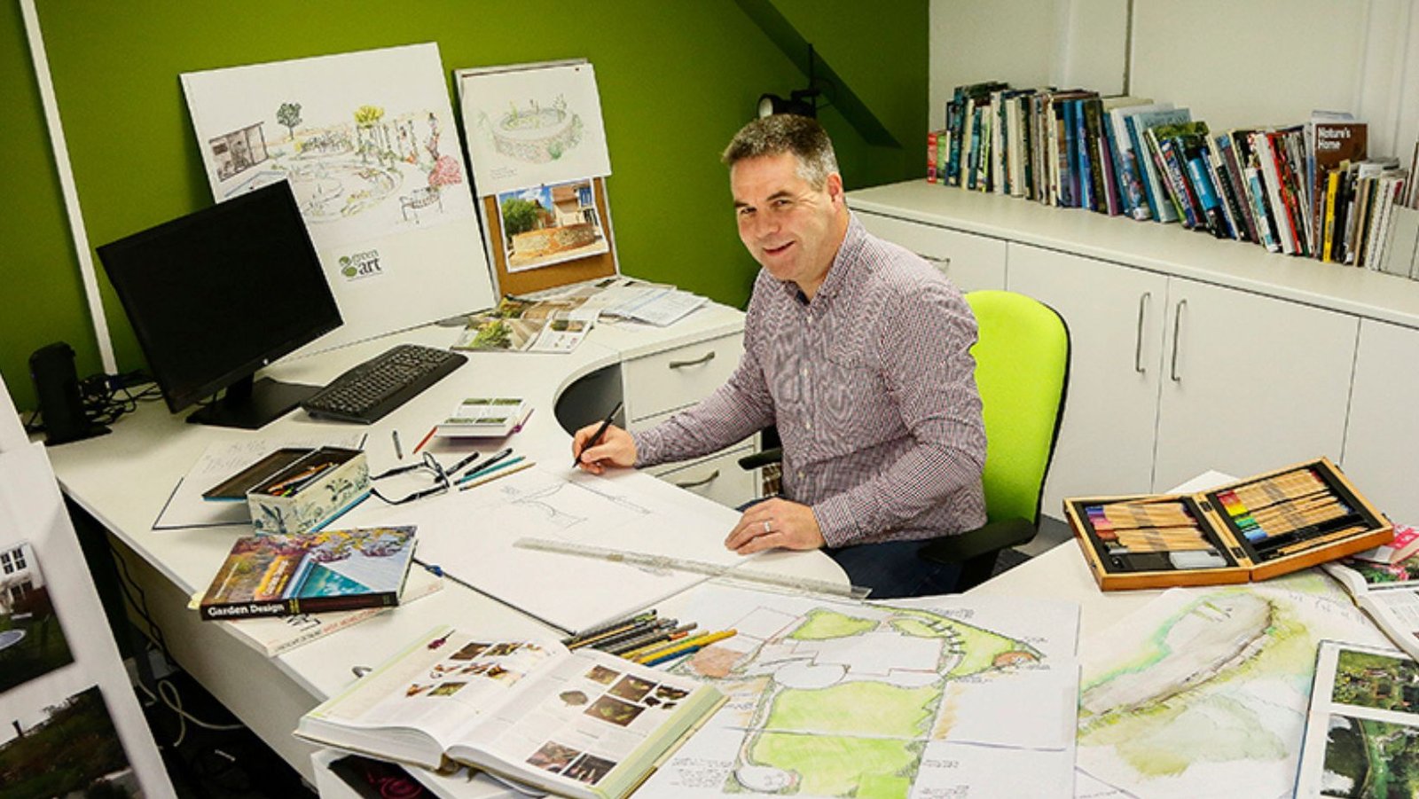GreenArt designer George Smith at his desk surrounded by garden design drawings